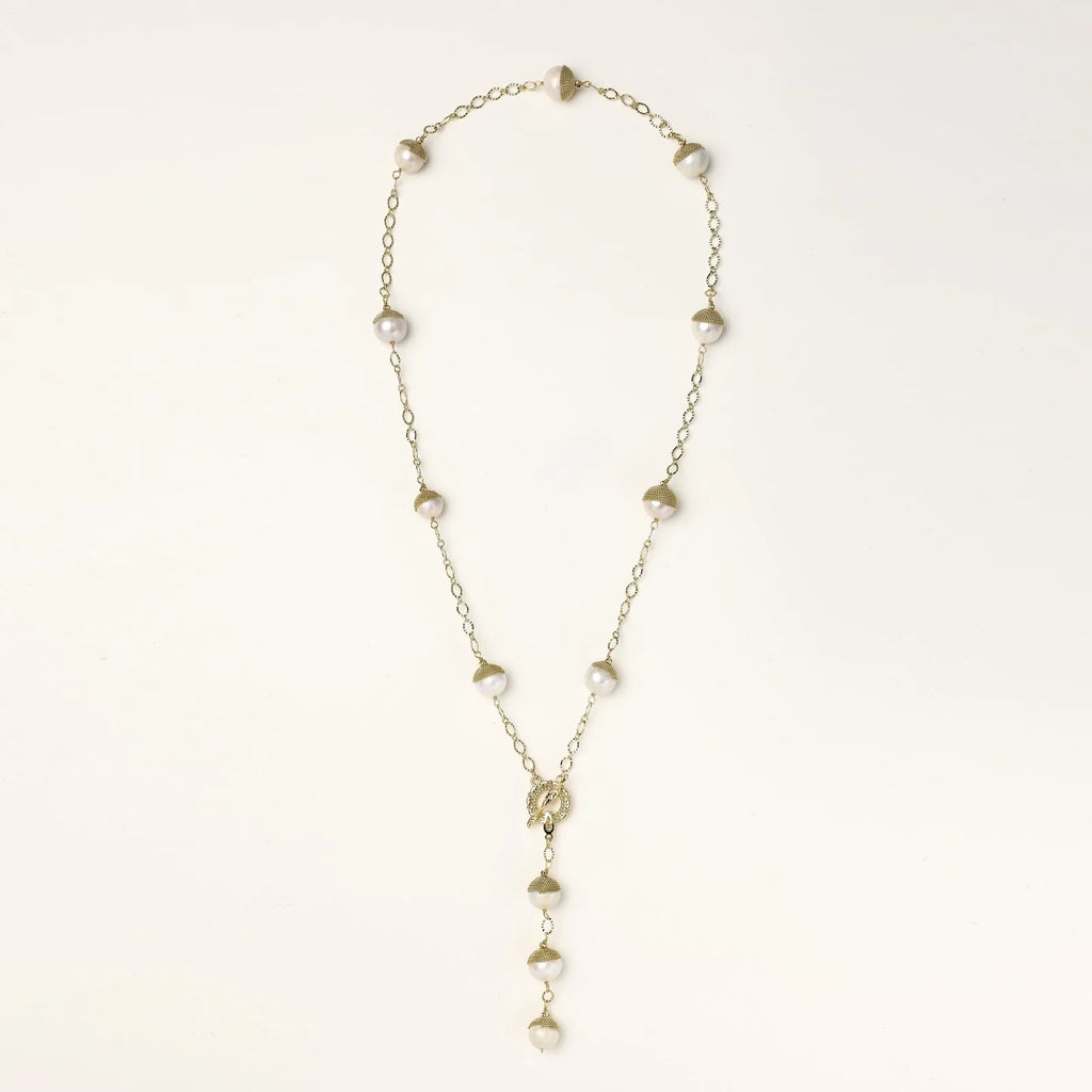 Gold-plated lariat necklace with baroque pearls and textured caps on cream background, showing adjustable Y-shaped design.