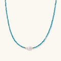 Delicate gold vermeil necklace with teal apatite beads and freshwater pearl on white background.