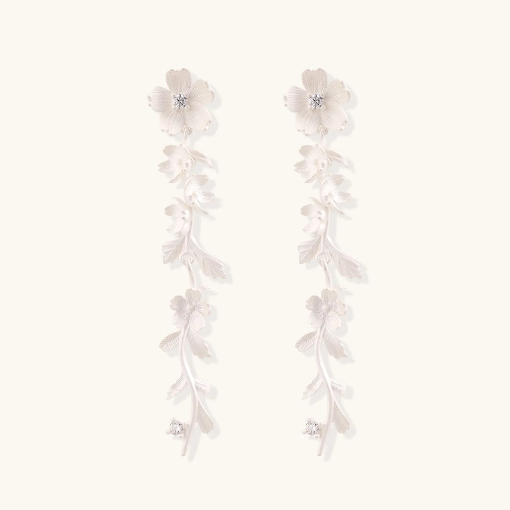 Long sterling silver drop earrings with delicate floral vine design and crystal accents on white background