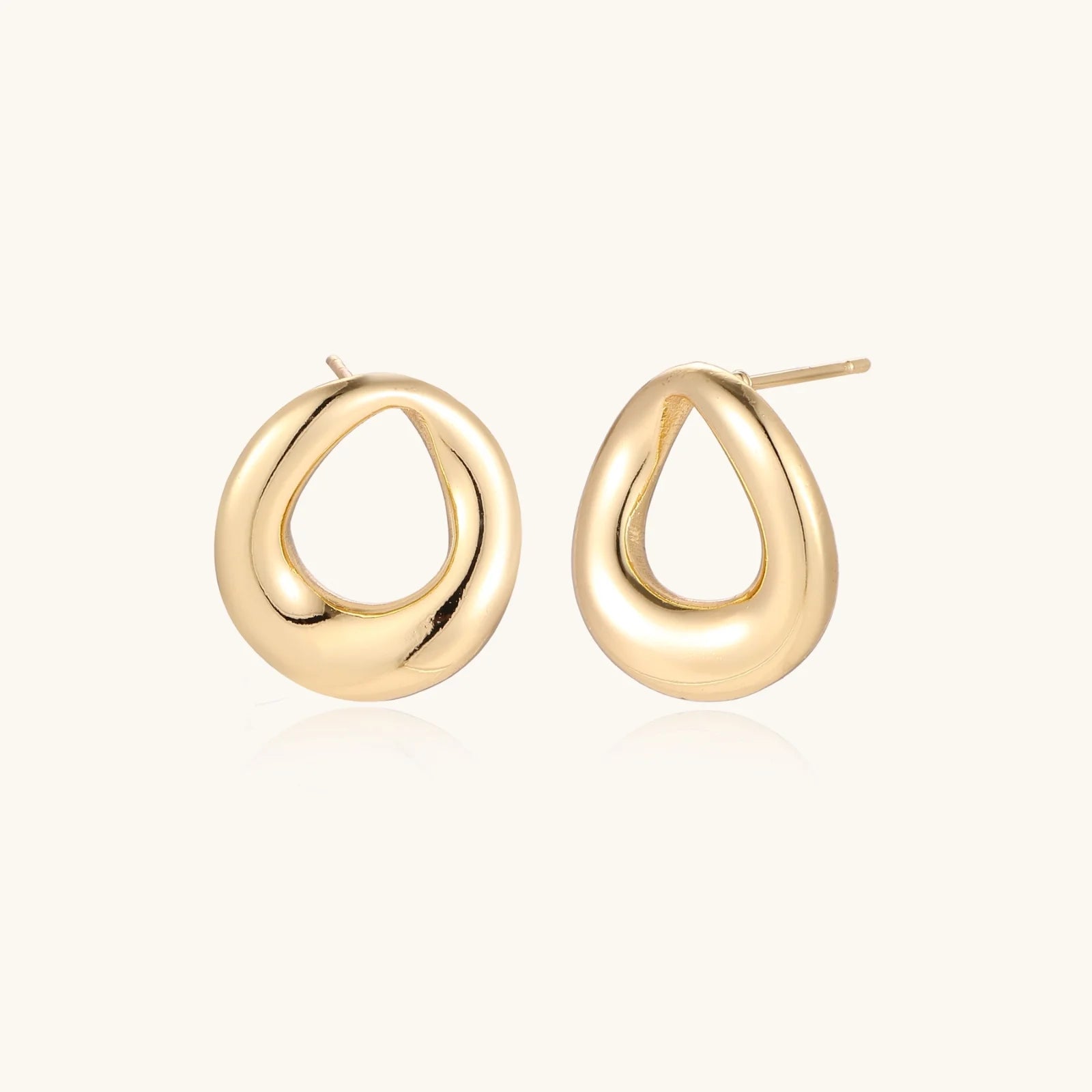 Pair of polished 18K gold-plated stainless steel teardrop earrings with hollow centers on cream background
