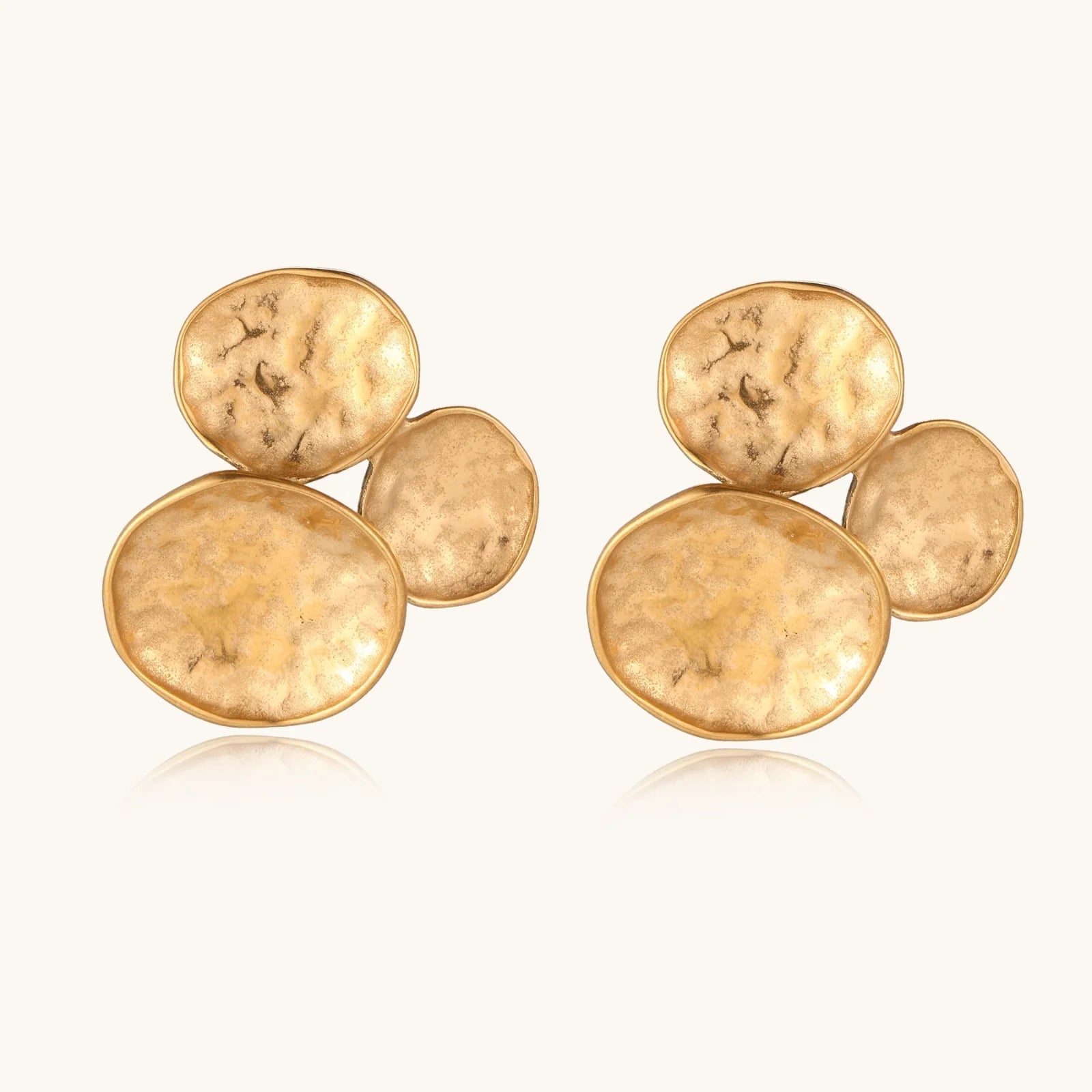 Three hammered gold discs clustered together forming organic statement earrings with textured surfaces