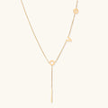 Gold Y-shaped necklace with L-O-V-E letter charms and vertical bar pendant on delicate chain against cream background