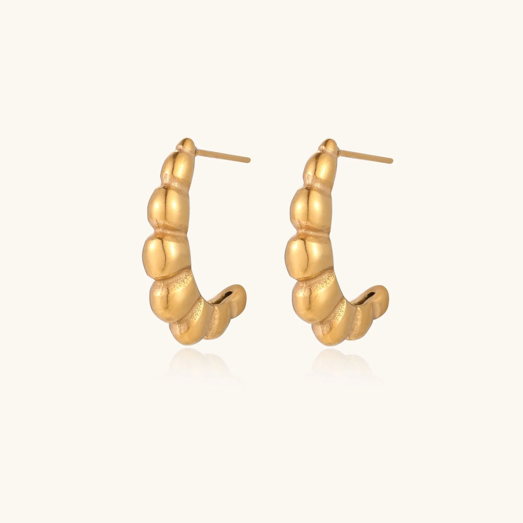 Gold-plated sculptural hoop earrings with chunky segmented design on cream background